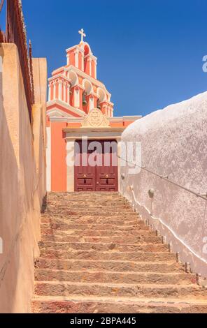 Looking up the stone steps that lead to church yard doors and the colourful bell tower above, in Fira, on the greek island of Santorini Foto Stock