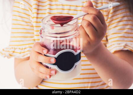 Bambina mangiare dessert lattiginoso con crema e gelatina fruttata in un vaso. Foto Stock