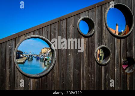 Chioggia, città della laguna veneta, vista sulla città attraverso i fori di un ponte di legno. Veneto, Italia, Europa. Foto Stock