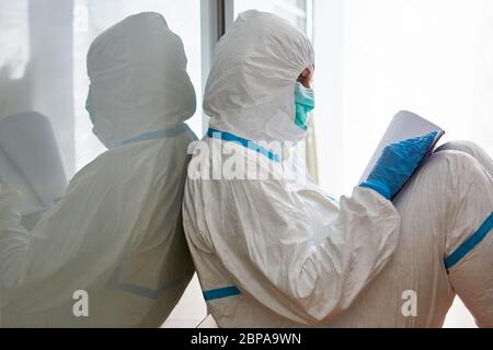 Dipendente del reparto sanitario in indumenti protettivi con checklist per il monitoraggio del contatto nella pandemia di coronavirus Foto Stock