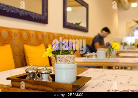 Tavolo in legno nel bar con fiori e sale, pepe e zucchero Foto Stock