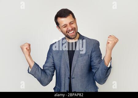 Ritratto di un giovane imprenditore energico che gode di successo. Il giovane uomo d'affari celebra il successo aziendale con le mani in su. Concetto vincitore. Foto Stock