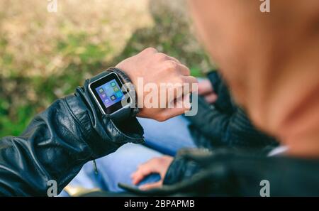 Irriconoscibile giovane guardando al suo smartwatch Foto Stock