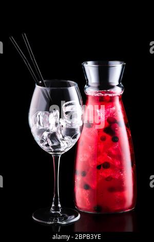 Vaso con sangria con frutti di bosco e un bicchiere di vino isolato su fondo nero Foto Stock