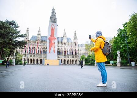 Vienna, Austria - 16 maggio 2019: uomo turistico viaggiatore che prende foto al telefono vienna City Hall sullo sfondo Foto Stock