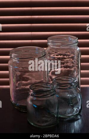 Quattro vasetti di vetro vuoti, usati e leggermente sporchi. Foto Stock