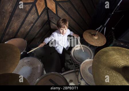 Il ragazzo impara a suonare la batteria. Il bambino dietro il kit tamburo. Foto Stock