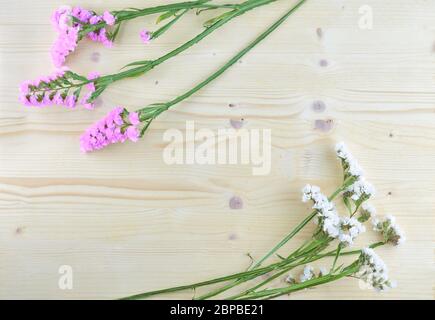 fiori bianchi e viola su sfondo di legno in aereo con copyspace Foto Stock