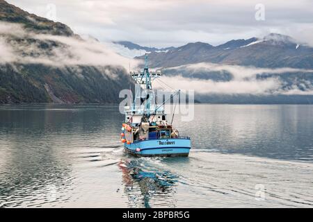 Una barca commerciale da pesca si dirige fuori sul canale di passaggio in Prince William Sound, Whittier, Alaska. Foto Stock