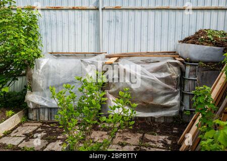 Contenitori di plastica sono riutilizzati per ridurre in concime organico rifiuti nel Garden. Fresco compostato terra dal compost bin. Nutriente-ricco vegetali trasformano in suolo. Foto Stock