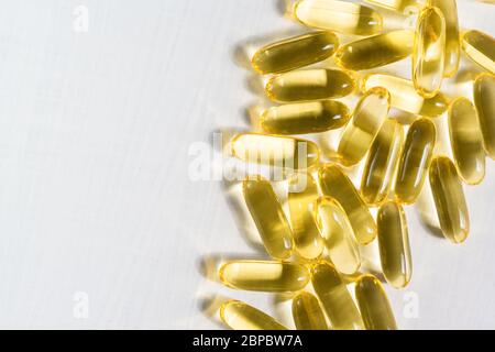 Capsule trasparenti di gelatina con olio di pesce sono su una tavola bianca. Acidi grassi polinsaturi Omega-3-essenziali Foto Stock