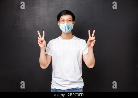 Stile di vita e concetto di persone. Simpatico ragazzo asiatico giovane hipster in t-shirt bianca e occhiali da sole rendono kawaii segni di pace e sorridente spensierato, rilassarsi Foto Stock