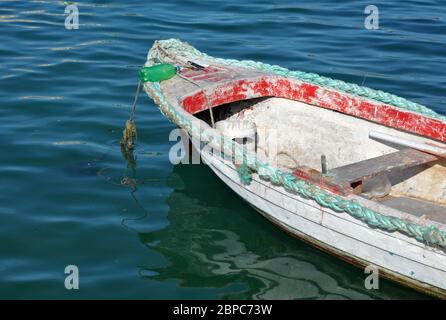 Un battello a remi stagionato galleggia nel porto di Marsaxlokk, un tradizionale villaggio di pescatori sulla costa sud-orientale dell'isola principale di Malta. Foto Stock