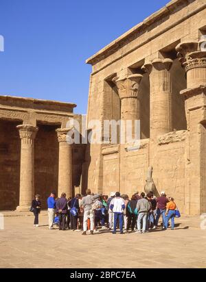 Gruppo con guida presso la Statua di Horus nel cortile del Tempio di Horus, Edfu, governatorato di Assuan, Egitto Foto Stock