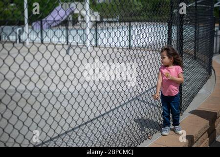 Manhattan, Kansas, Stati Uniti. 17 maggio 2020. MAIYA GONZALEZ, 2.5 anni, si trova all'ingresso della piscina Cico, ora chiusa. Con la chiusura delle piscine pubbliche i genitori devono trovare nuovi modi per intrattenere i loro bambini durante la pandemia COVID-19. Credit: Luke Townsend/ZUMA Wire/Alamy Live News Foto Stock