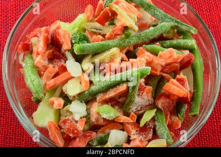 Surgelare in un recipiente di vetro le verdure miste di carote, fagioli verdi, peperoni rossi, carote, cipolle e funghi Foto Stock