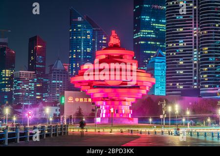 QINGDAO, CINA - NOVEMBRE 13: Vista notturna del monumento della Piazza del quarto Maggio e degli edifici del quartiere finanziario della città il 13 Novembre 2019 a Qingdao Foto Stock