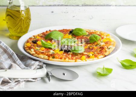 Gustosa pizza salame. Pizza con foglie di basilico su piatto. Foto Stock