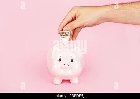 Banca piggy e denaro contante cento dollari fatture su sfondo rosa. Disposizione piatta, vista dall'alto, sovratesta, mockup, template Foto Stock