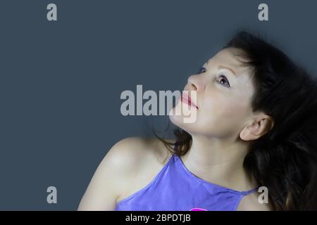 Ritratto di una bella donna di mezza età alla moda con lunghi capelli scuri, che posa su uno sfondo grigio scuro. Il concetto di preservare i giovani in qualsiasi ag Foto Stock