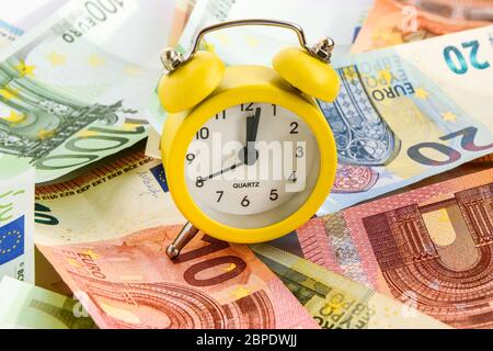 Sveglia con carta euro moneta 10, 20, 50, 100, sveglia sulle banconote, Tempo è denaro, Tempo di fare soldi. Sveglia e dollari, orologio standin Foto Stock