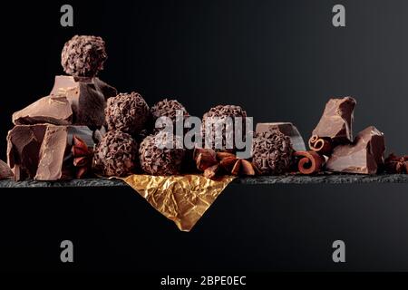 Cioccolato, bastoncini di cannella e anice su sfondo scuro. Spazio di copia. Foto Stock