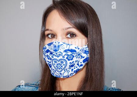 Giovane Donna indossa il viso fatto in casa, maschera protettiva. Isolamento automatico, quarantena causato di Covid 19, Corona Virus. Protezione contro le batterie Foto Stock