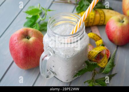 Frullato biologico di ortica, mela e banana in vaso. Concetto di stile di vita sano. Nastro Mesure Foto Stock