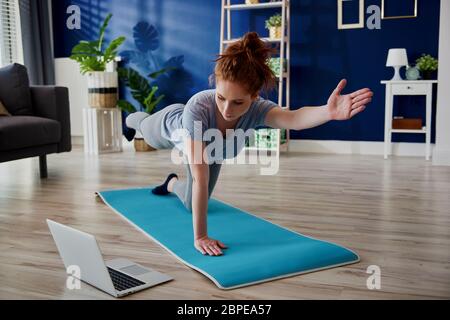 Donna che prende la lezione in linea di workout domestico Foto Stock