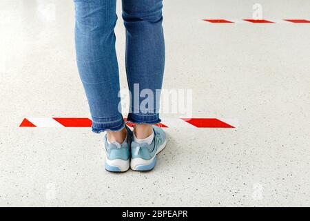 La gente sta in linea mantenendo la distanza sociale, Donna in piedi dietro una linea di allarme durante la quarantena di coronavirus della covid 19. Shopping sicuro, sociale Foto Stock