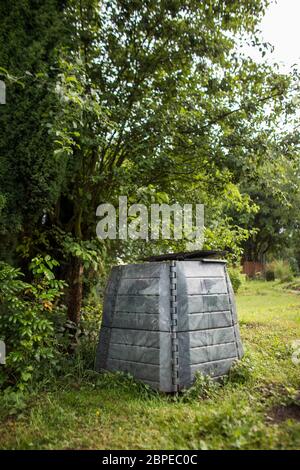 Compostore di plastica in un giardino - riempito con materiale organico decadente da usare come fertilizzante per coltivare verdure biologiche, coltivate in casa (D poco profondo Foto Stock