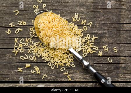 Alfabeto di pasta a cucchiaio sul vecchio tavolo in legno Foto Stock