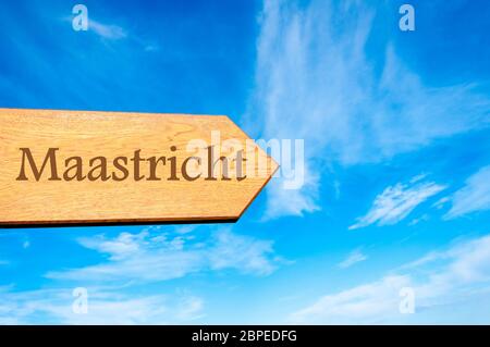 Freccia in legno che indica la destinazione MAASTRICHT, Paesi Bassi contro il cielo blu chiaro con spazio di copia disponibile. Informazioni concettuali sulla destinazione del viaggio Foto Stock