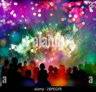 Nächtliches Feuerwerk mit bunten Licht- und Glitzermustern, Konfettiregen bunter und Zuschauer-Silhouetten, Mixed Media Foto Stock