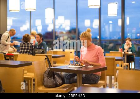 Giovani viaggiatori femmina mangiare la pizza all'aeroporto ristorante mentre si è in attesa di late night della partenza del volo. Foto Stock