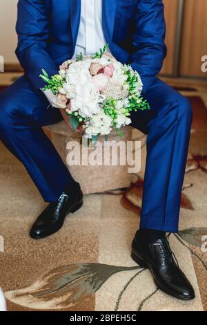 fiance in un vestito blu scuro tiene un bouquet di nozze fatto di peonies Foto Stock