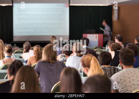 Altoparlante dando un talk durante la riunione di affari. Il pubblico in sala conferenza. Business e imprenditorialità. Concentrarsi sulle persone non riconoscibile dalla parte posteriore. Foto Stock