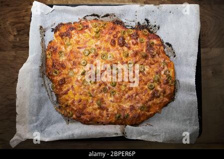 Pizza fatta in casa con pomodoro e formaggio su un tavolo di legno in una cucina rustica. Sfondo tradizionale della pizza. Foto Stock