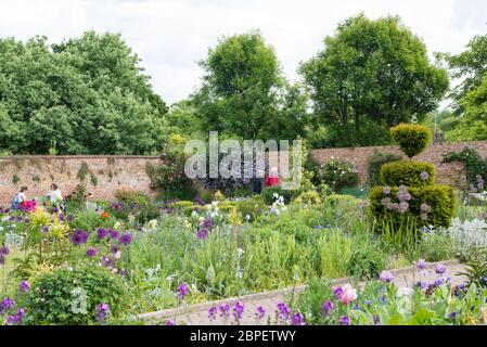 Le persone si rilassano nel giardino murato dell'Eastcote House Gardens durante una giornata soleggiata e calda in tarda primavera. Inghilterra, Regno Unito. Foto Stock