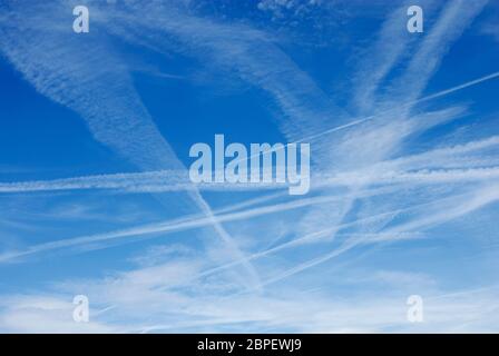 Contrails da aerei che volano alto in alto, visto contro cielo blu, Kent, Inghilterra Foto Stock