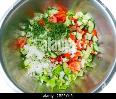 Vista dall'alto degli ingredienti per insalate in casa nel recipiente in metallo. Cetrioli, pomodori, cipolle e aneto non stagionati Foto Stock