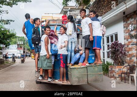 Un gruppo di filippini locali si aggrappano sul retro di un autobus mentre si accelera nella città di El Nido, Palawan, Filippine. Foto Stock