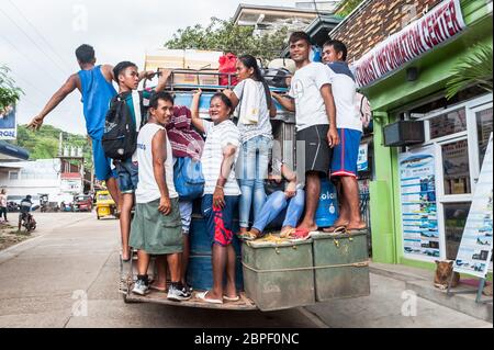 Un gruppo di filippini locali si aggrappano sul retro di un autobus mentre si accelera nella città di El Nido, Palawan, Filippine. Foto Stock