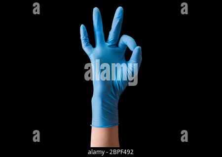 Mano del medico in guanti medici sterili in gesto di OK isolato su nero Foto Stock