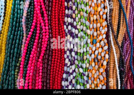 Sfondo colorato e Collana fatta di pietre preziose e di perle colorate esposte in un negozio. Semi preziosi gioielli. Foto Stock