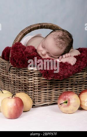 Un neonato allegro che dormiva all'interno di un cesto di vimini Foto Stock