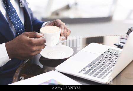 Uomo d'affari irriconoscibile che ha il caffè che lavora sul laptop in caffè, Closeup Foto Stock