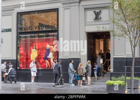 Le persone si accodano a distanza di sicurezza per entrare nel negozio Louis Vuitton di George Street, Sydney, poiché le restrizioni agevolano e altri negozi si aprono di nuovo per affari Foto Stock