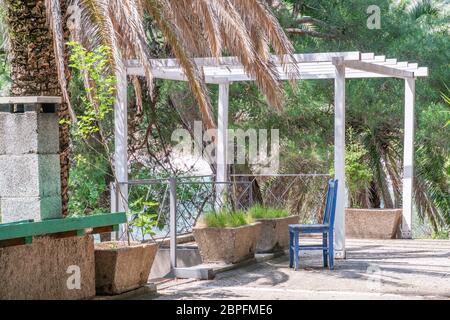 gazebo bianco abbandonato sul mare con una sedia blu Foto Stock