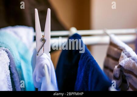 Un bianco clothespin pende una vestiti appesi a un rack di asciugatura. Asciugare il bucato Foto Stock